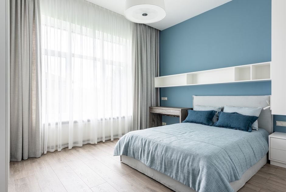 Slaapkamer met blauw en grijs beddengoed.